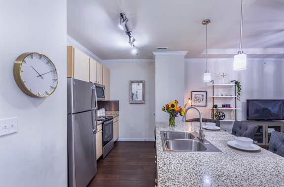 A modern kitchen with a granite countertop and stainless steel appliances.