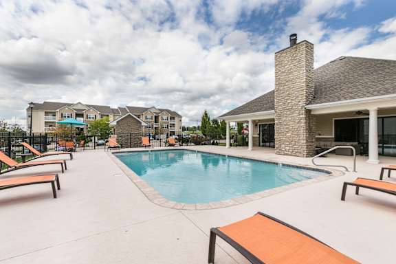A pool surrounded by lounge chairs and a building in the background.