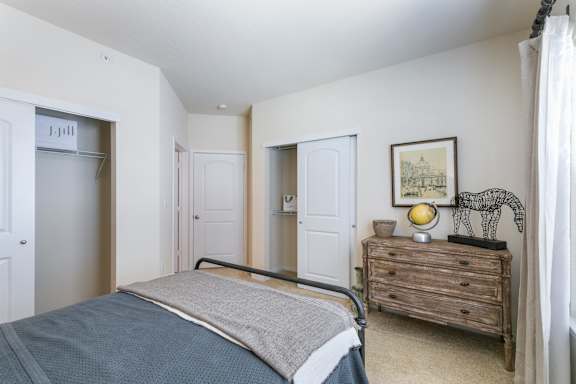 A bedroom with a bed, dresser, and a painting on the wall.