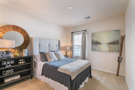 A bedroom with a large bed and a painting on the wall.