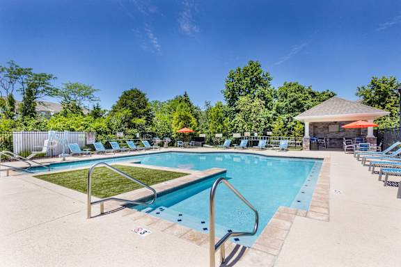 A large outdoor swimming pool surrounded by lounge chairs and umbrellas.