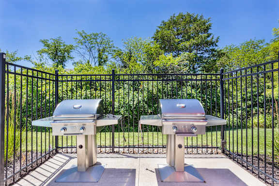 Two grills are surrounded by a black fence.