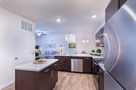 A modern kitchen with stainless steel appliances and wooden flooring.
