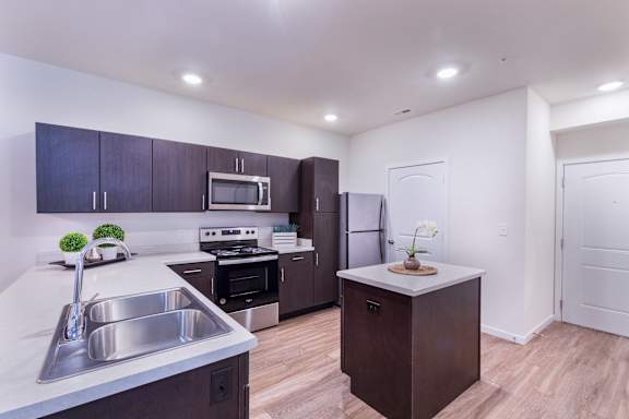 A kitchen with a sink, stove, and refrigerator.