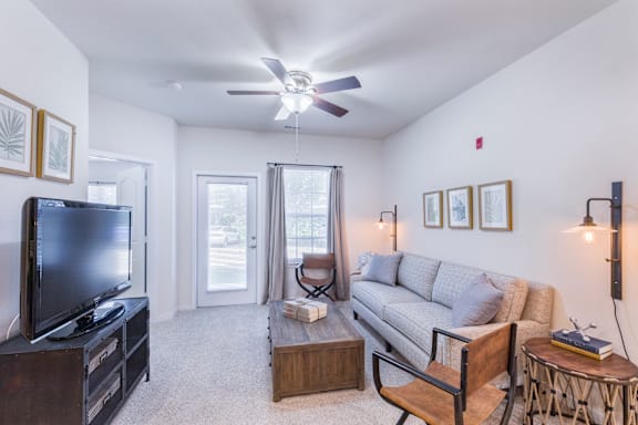 A living room with a television, couch, and a ceiling fan.