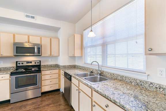 A kitchen with a granite countertop and stainless steel appliances.