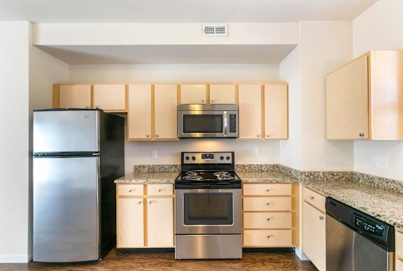 A kitchen with a stainless steel refrigerator, microwave, oven, and dishwasher.