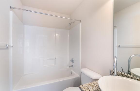 A white bathroom with a tub, toilet, and sink.
