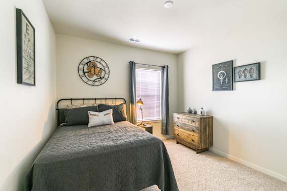 A bedroom with a bed, dresser, and window.