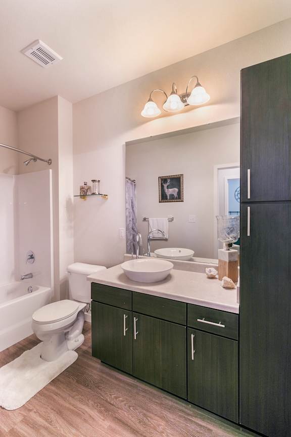 A bathroom with a toilet, sink, and a mirror.