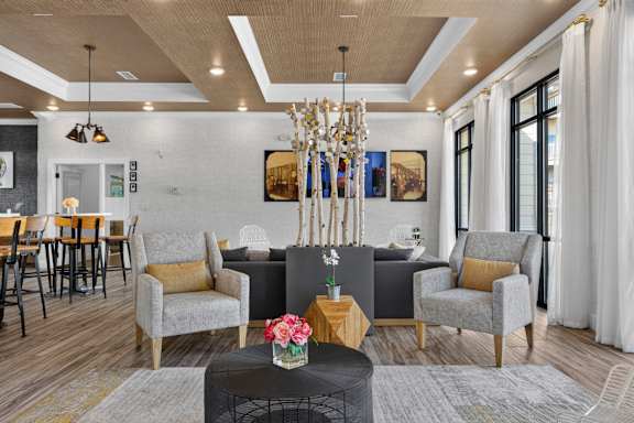 A living room with a grey sofa, a grey armchair, a wooden coffee table, and a chandelier.