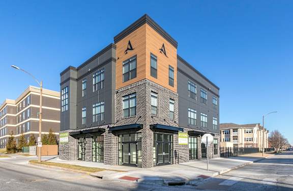 A modern building with a black and brown facade stands on a street corner.