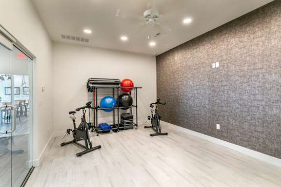 A room with a wall covered in a brown textured wallpaper and a wooden floor.