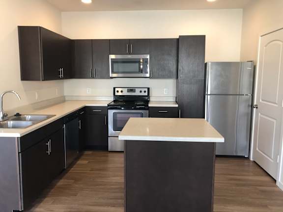 A kitchen with black cabinets and a white island.
