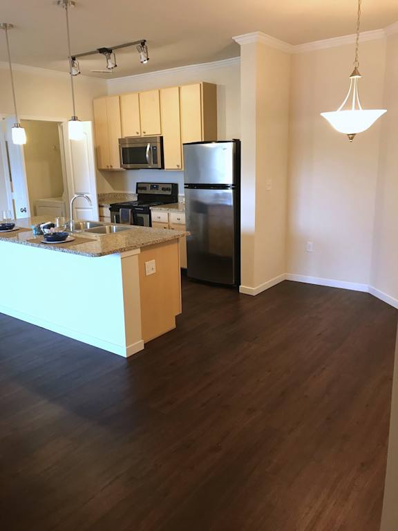 A kitchen with wooden floors and a black refrigerator.