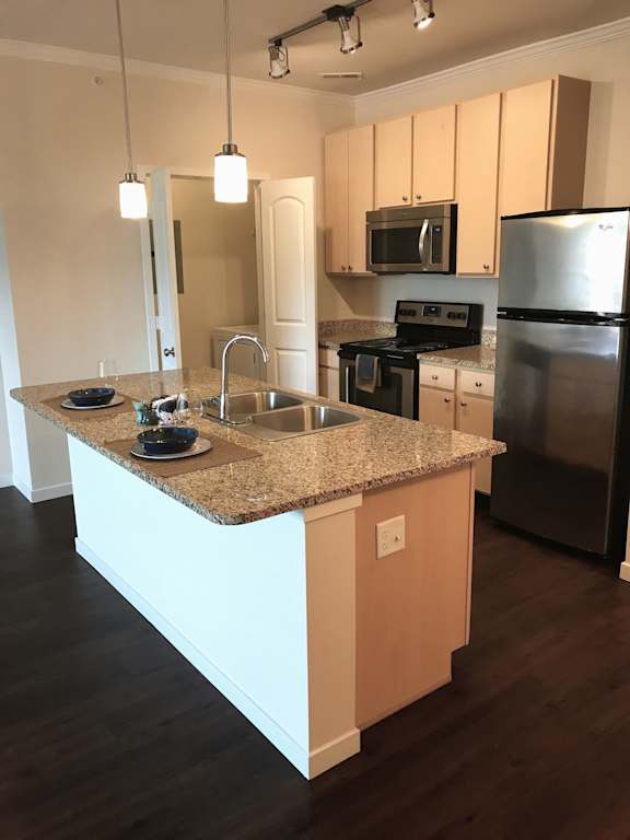 A kitchen with a granite countertop and stainless steel appliances.