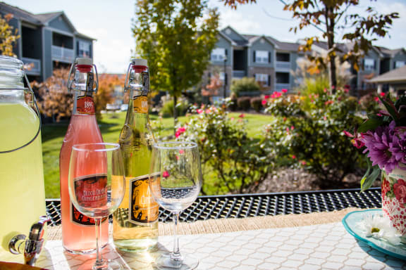 a bottle of wine and glasses on a patio table  at Aventura at Richmond, St. Peters