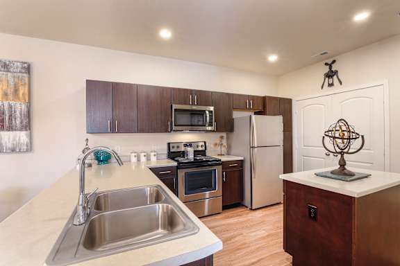 A kitchen with a sink, stove, and refrigerator.