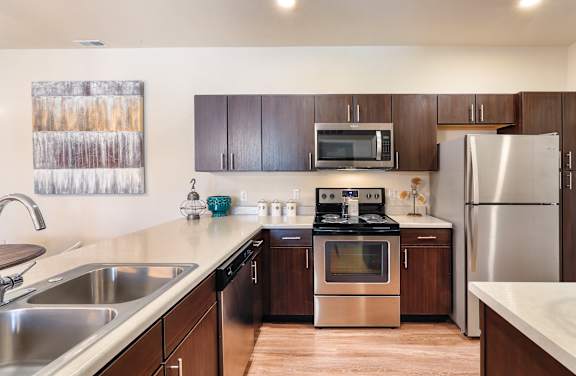 A modern kitchen with dark wood cabinets and stainless steel appliances.