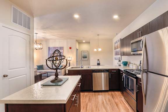 A modern kitchen with a white countertop and stainless steel appliances.