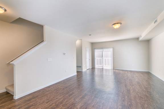 A spacious room with wooden flooring and white walls.