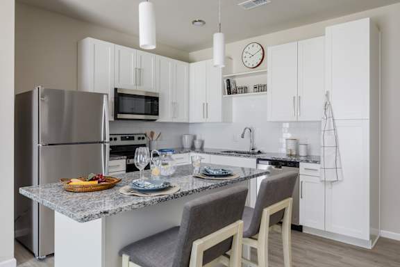 A modern kitchen with a granite countertop and stainless steel appliances.