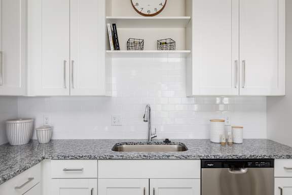 A kitchen with white cabinets and a granite countertop.