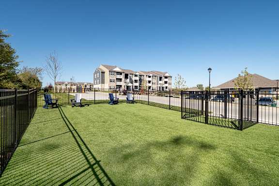 A grassy area in front of a building with a black fence.