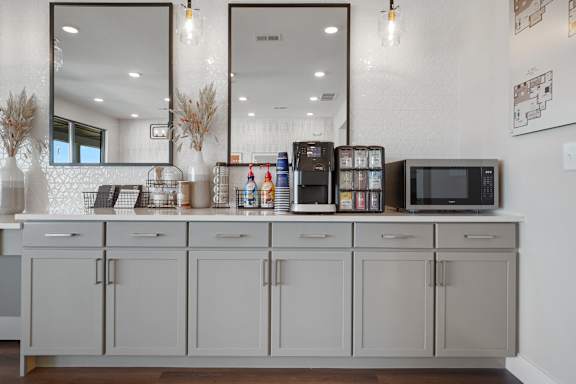 A kitchen with a white counter and grey cabinets.