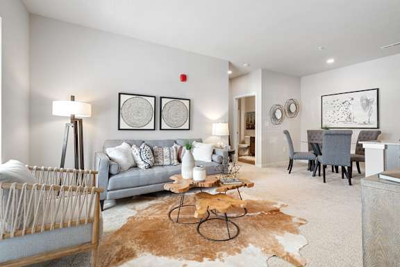 A living room with a grey couch, a brown cowhide rug, and a wooden coffee table.