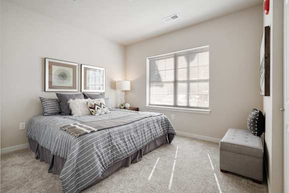 A bedroom with a bed, two lamps, and a window.