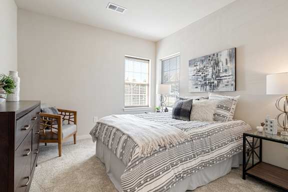 A bedroom with a bed, nightstand, and chair.