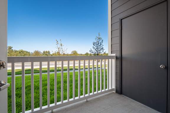 A balcony with a white railing and a black door.