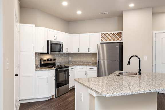 A kitchen with white cabinets and a granite countertop.
