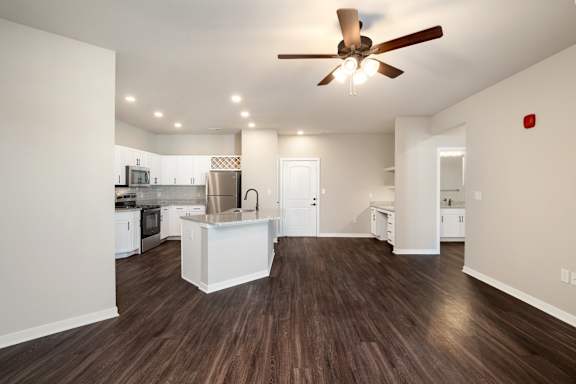 A modern kitchen with white appliances and a wooden floor.
