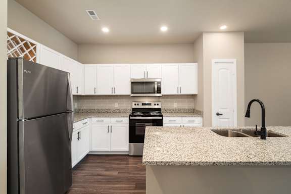 A kitchen with a refrigerator, oven, and sink.