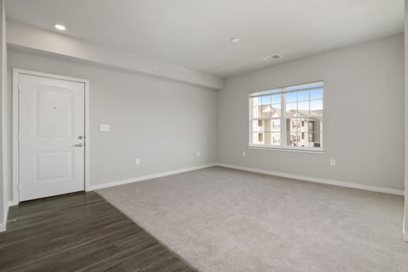 an empty living room with a white door and a window