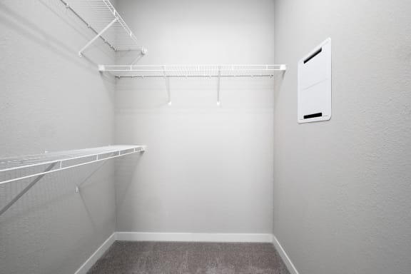 a spacious walk in closet in a white room with a hanging rack on the wall
