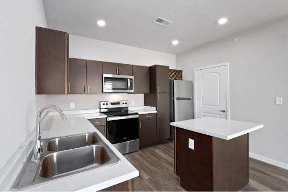 A kitchen with brown cabinets and a white countertop at Aventura at Wentzville I & II Apartments, Wentzville