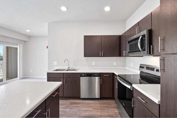 A modern kitchen with dark wood cabinets and stainless steel appliances at Aventura at Wentzville I & II Apartments, Missouri