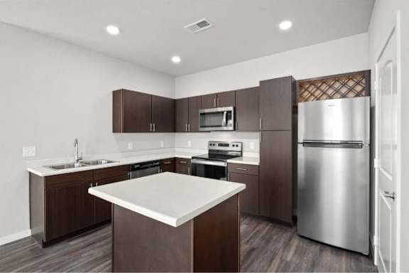 A modern kitchen with dark brown cabinets and stainless steel appliances at Aventura at Wentzville I & II Apartments, Wentzville, MO, 63385