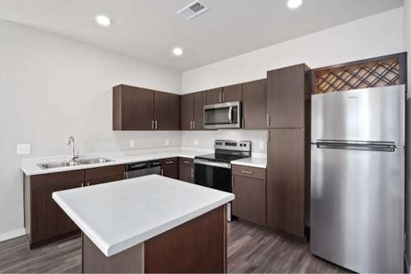 A modern kitchen with a stainless steel refrigerator and wooden cabinets at Aventura at Wentzville I & II Apartments, Wentzville, 63385