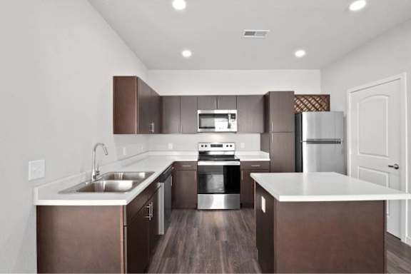 A modern kitchen with dark brown cabinets and stainless steel appliances at Aventura at Wentzville I & II Apartments, Wentzville, Missouri
