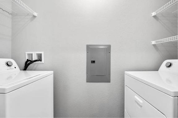 A laundry room with a washer and dryer on either side of a metal cabinet at Aventura at Wentzville I & II Apartments, Missouri, 63385