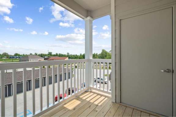 A balcony with a white door and a view of a parking lot at Aventura at Wentzville I & II Apartments, Wentzville, MO, 63385