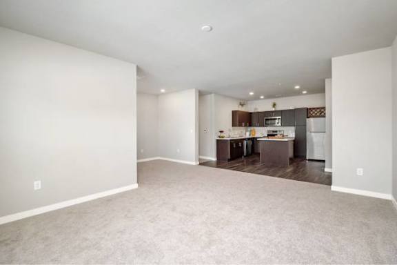 A spacious living room with a kitchen in the background at Aventura at Wentzville I &amp; II Apartments, Wentzville, MO