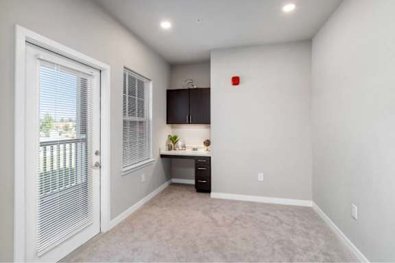 A room with a desk and a window with blinds at Aventura at Wentzville I &amp; II Apartments, Wentzville