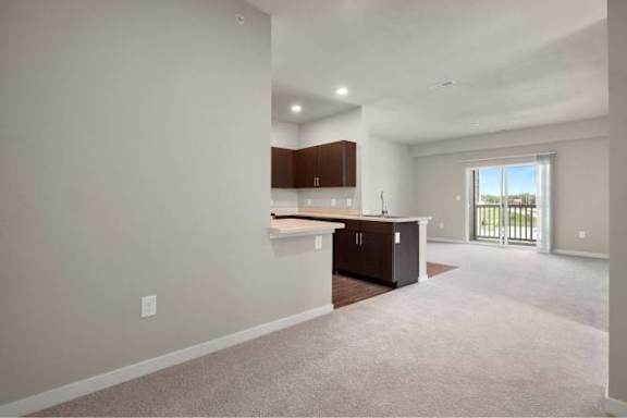 A spacious living room with a kitchen area in the background at Aventura at Wentzville I &amp; II Apartments, Wentzville