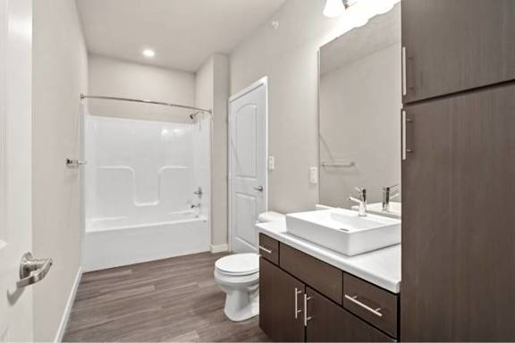 A white toilet sits in a bathroom with a white sink and a white bathtub at Aventura at Wentzville I &amp; II Apartments, Wentzville, MO, 63385