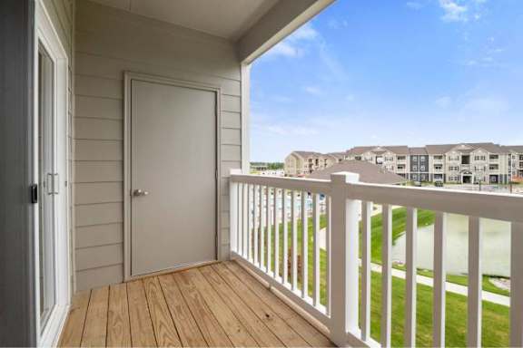 A balcony with a white door and a white railing overlooking a grassy area at Aventura at Wentzville I &amp; II Apartments, Wentzville, 63385